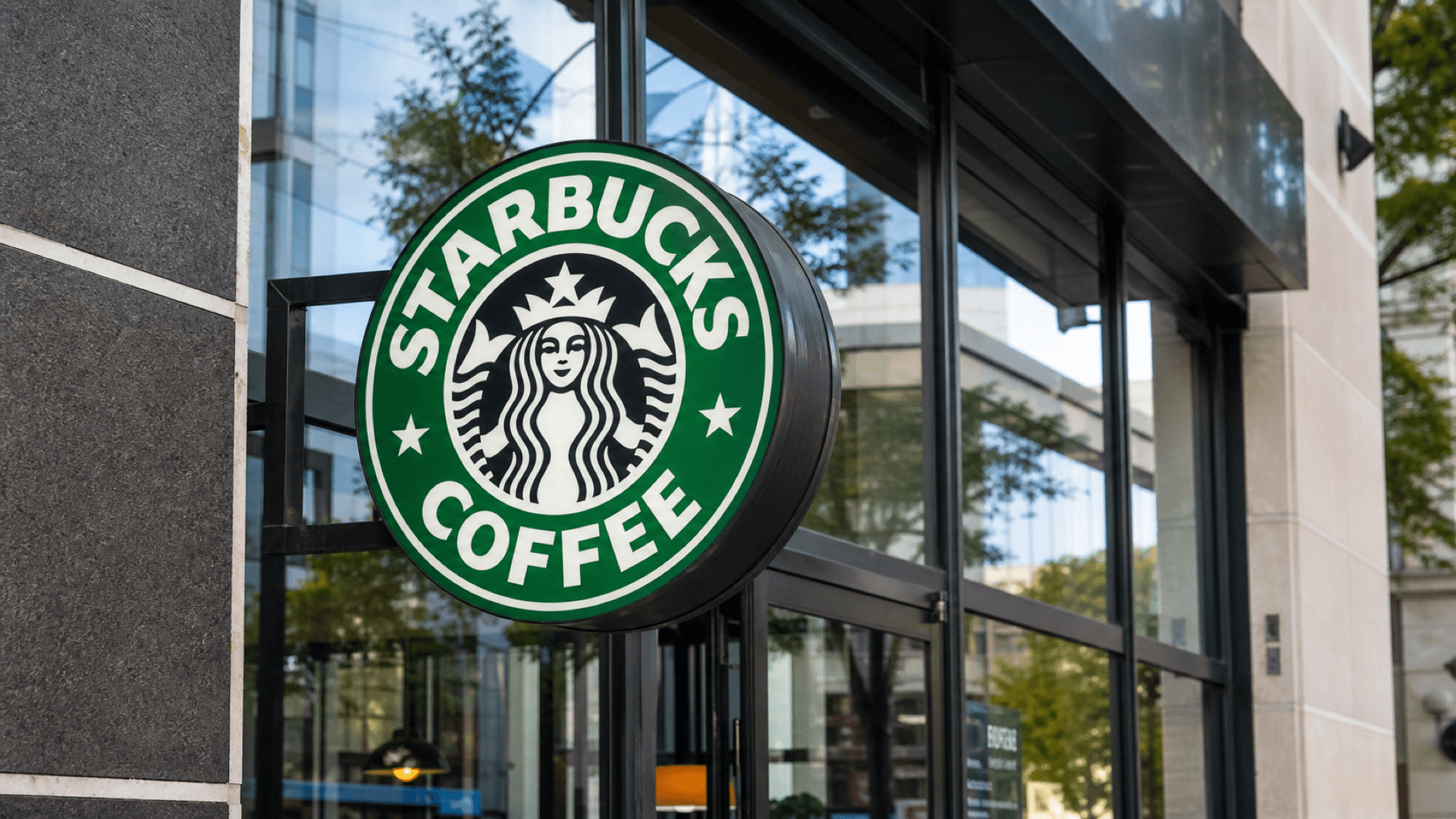 A close-up of a Starbucks Coffee sign outside a modern cafe storefront