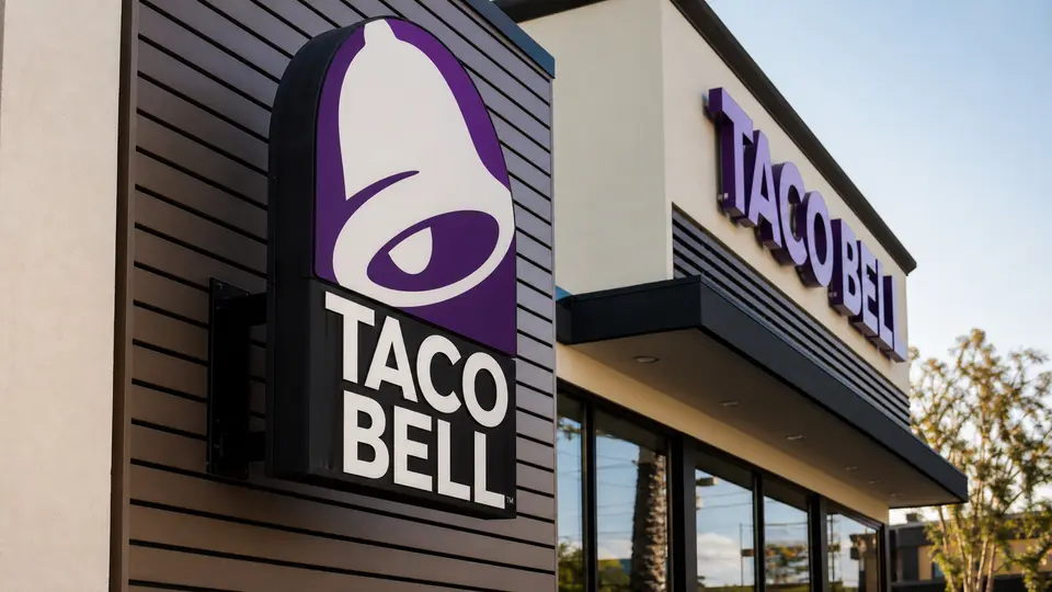 A close-up of a Taco Bell sign outside a modern restaurant storefront
