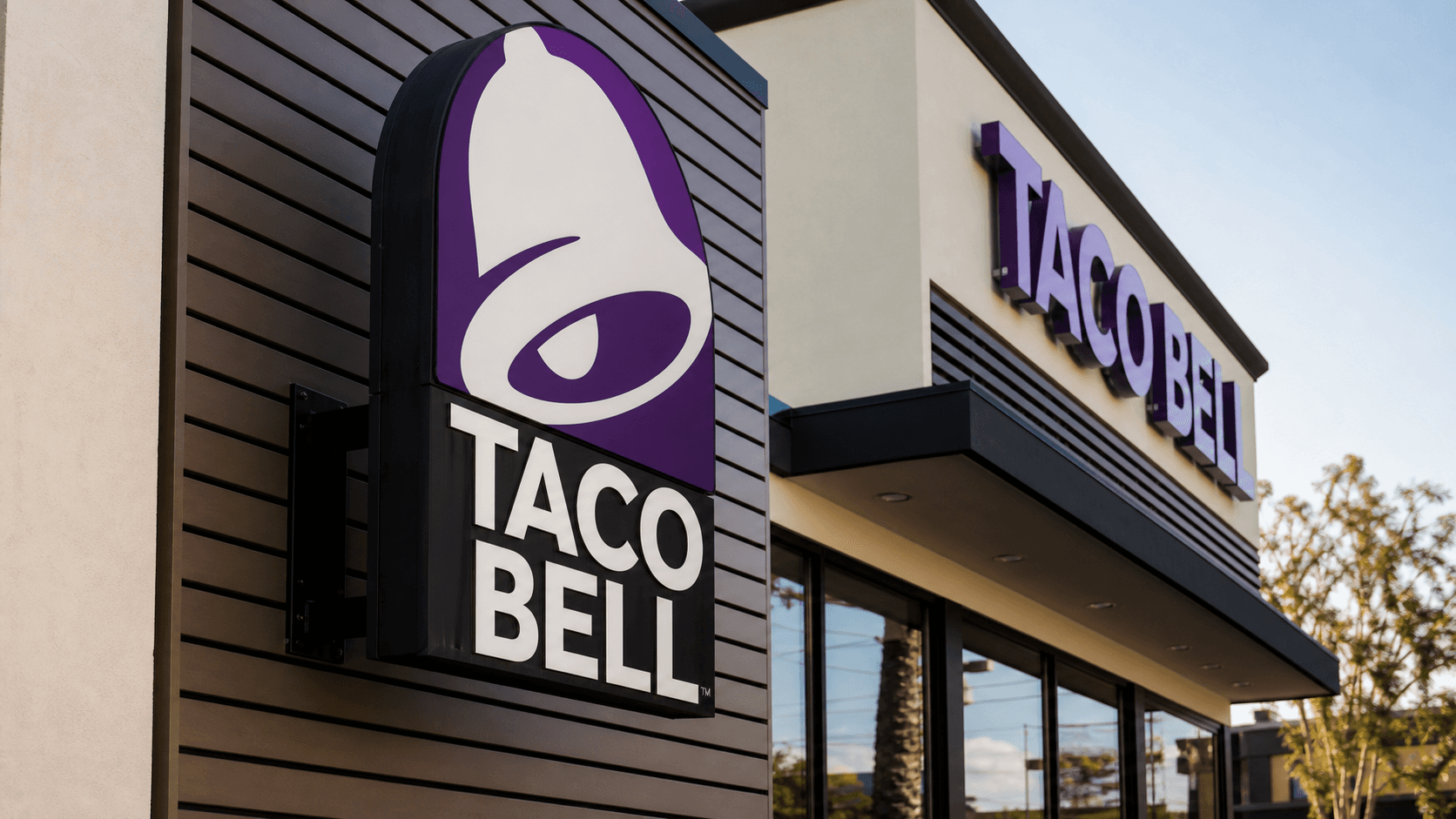 A close-up of a Taco Bell sign outside a modern restaurant storefront