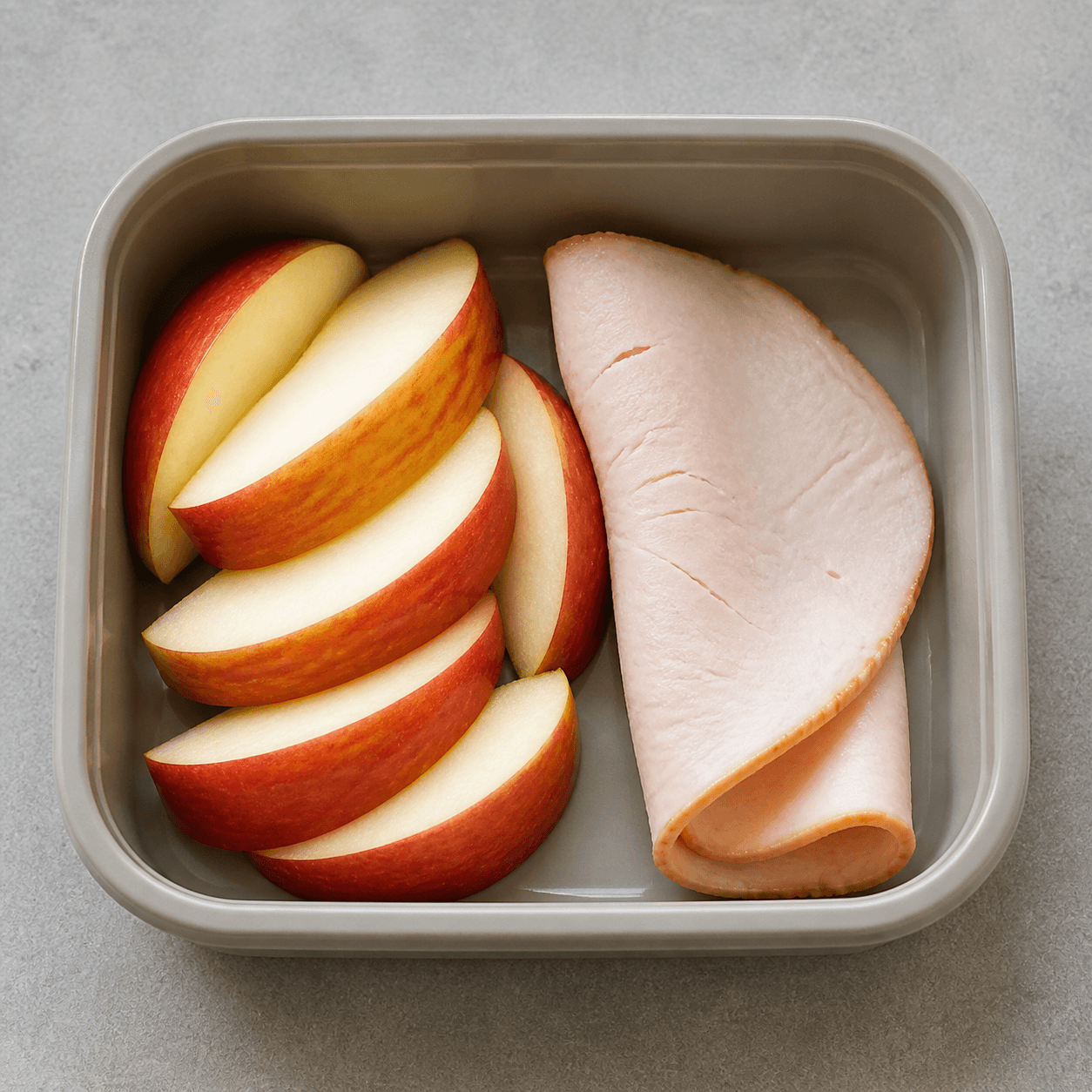 A sliced apple with one folded slice of turkey breast
